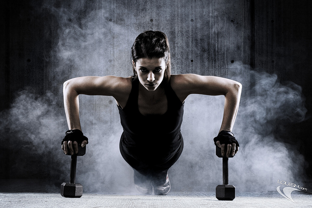 Fotografia do Stock: Young Woman Athlete Doing Pushups As Part Of  Bodybuilding Training. Woman with big boobs.